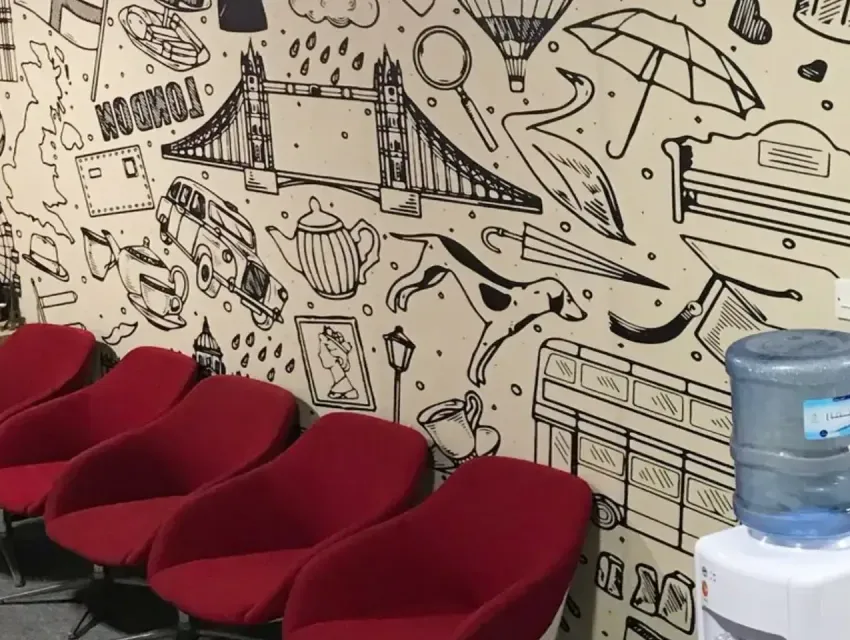 Black and white printed wall mural covering a full office waiting area wall above red lounge chairs