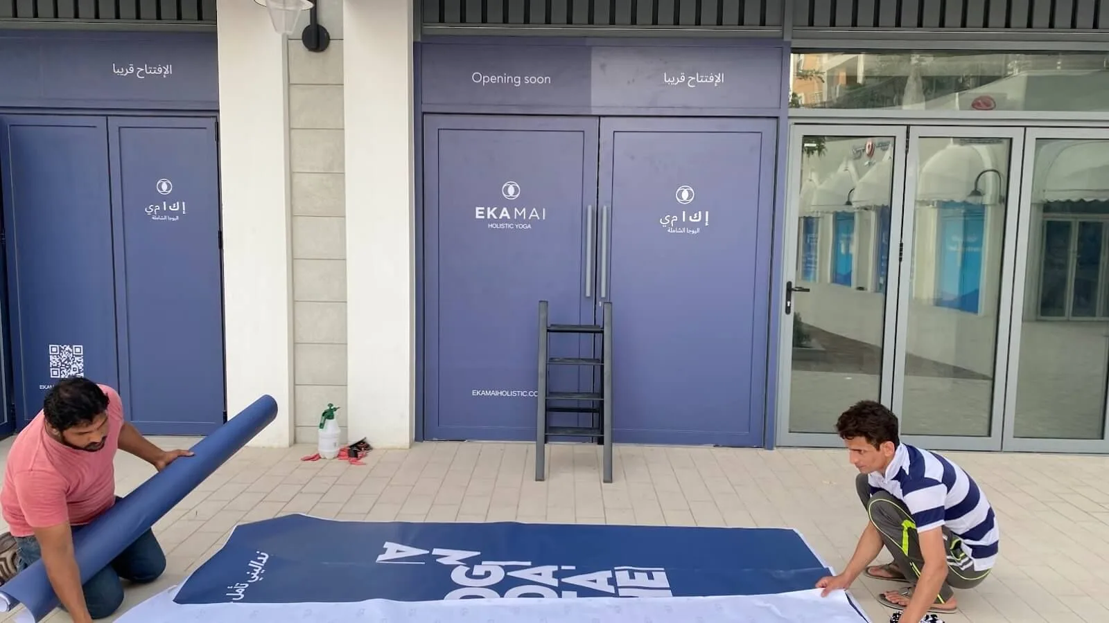 Installers fitting a large printed banner at a building entrance
