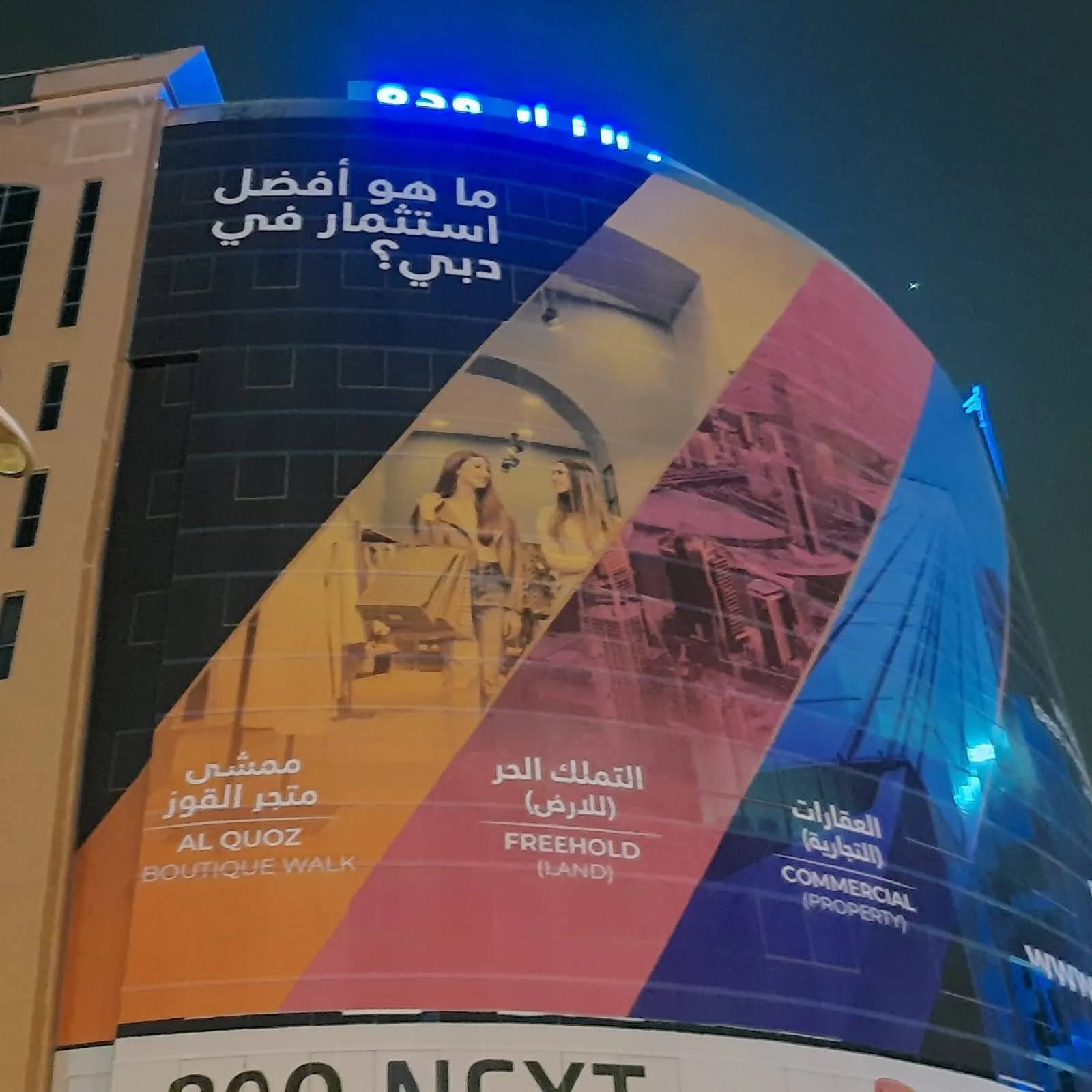 Large printed building wrap covering a curved tower facade in Dubai