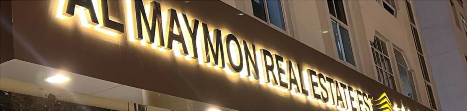 Gold halo-lit channel letters on a real estate office fascia at night