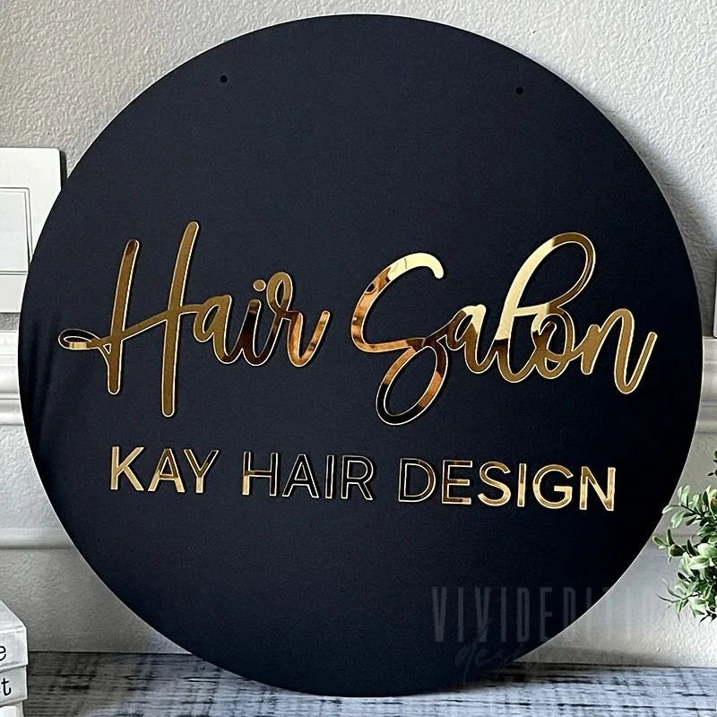 Round black plaque with cut gold acrylic script lettering for a hair salon