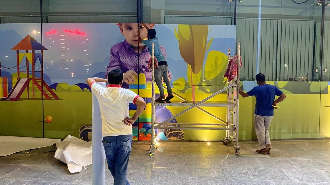 Installers on a tower fitting a printed wall mural, custom wallpaper printing by Bayan Signage
