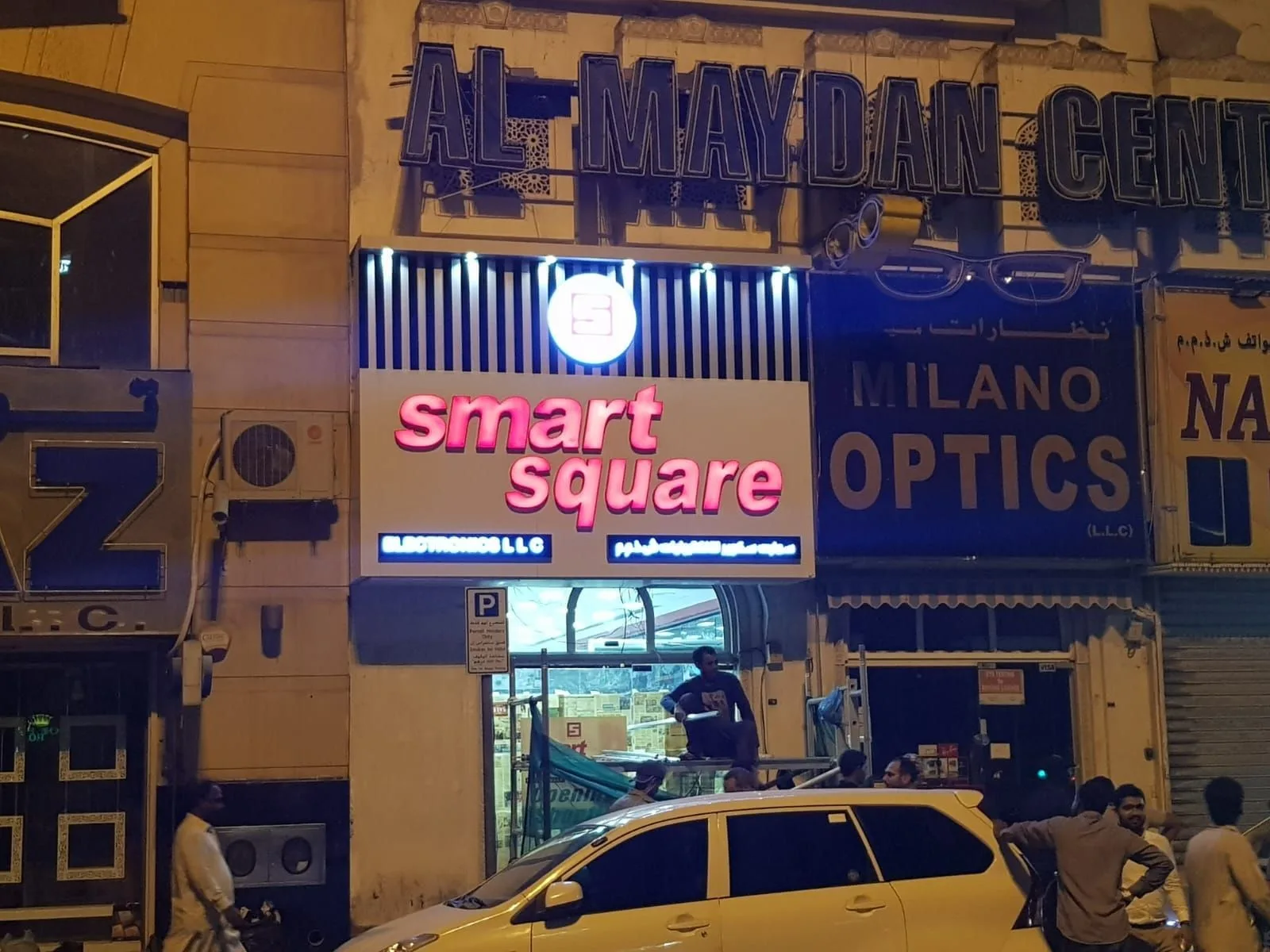 Row of shopfronts at night with outdoor light box fascia signs and lit letters