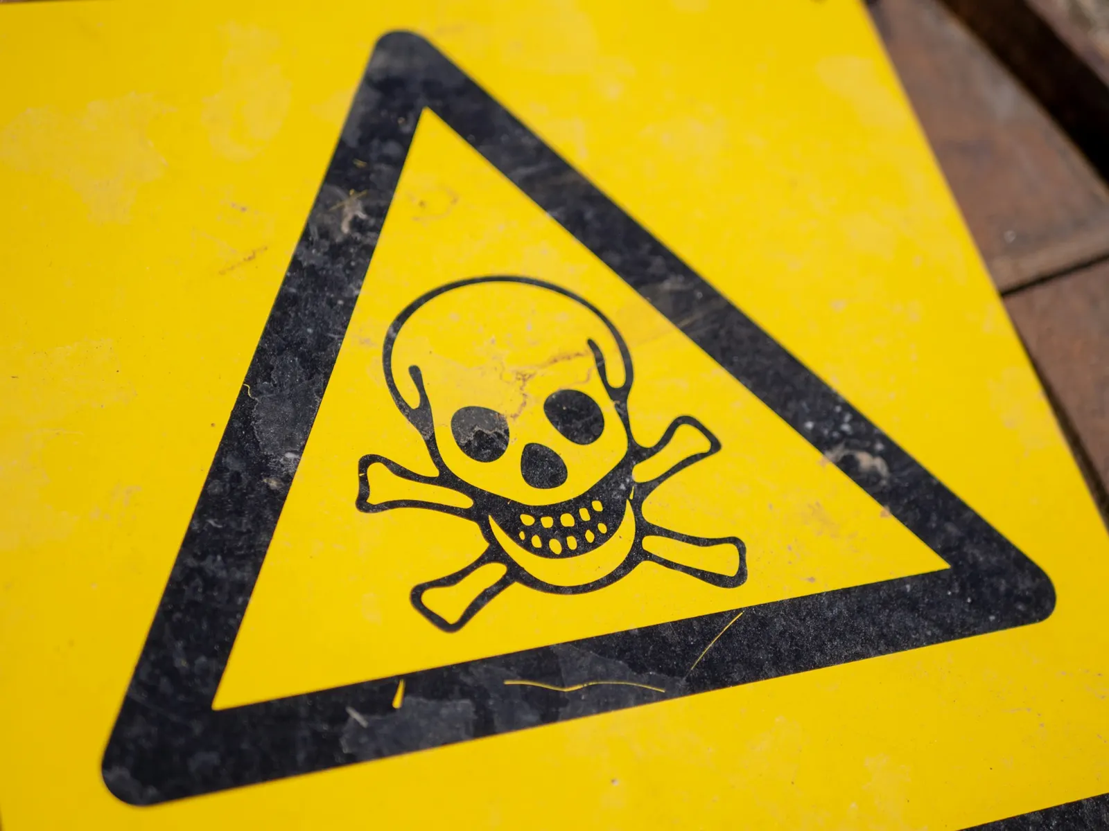 Yellow triangular chemical hazard sign with a black skull and crossbones toxic symbol