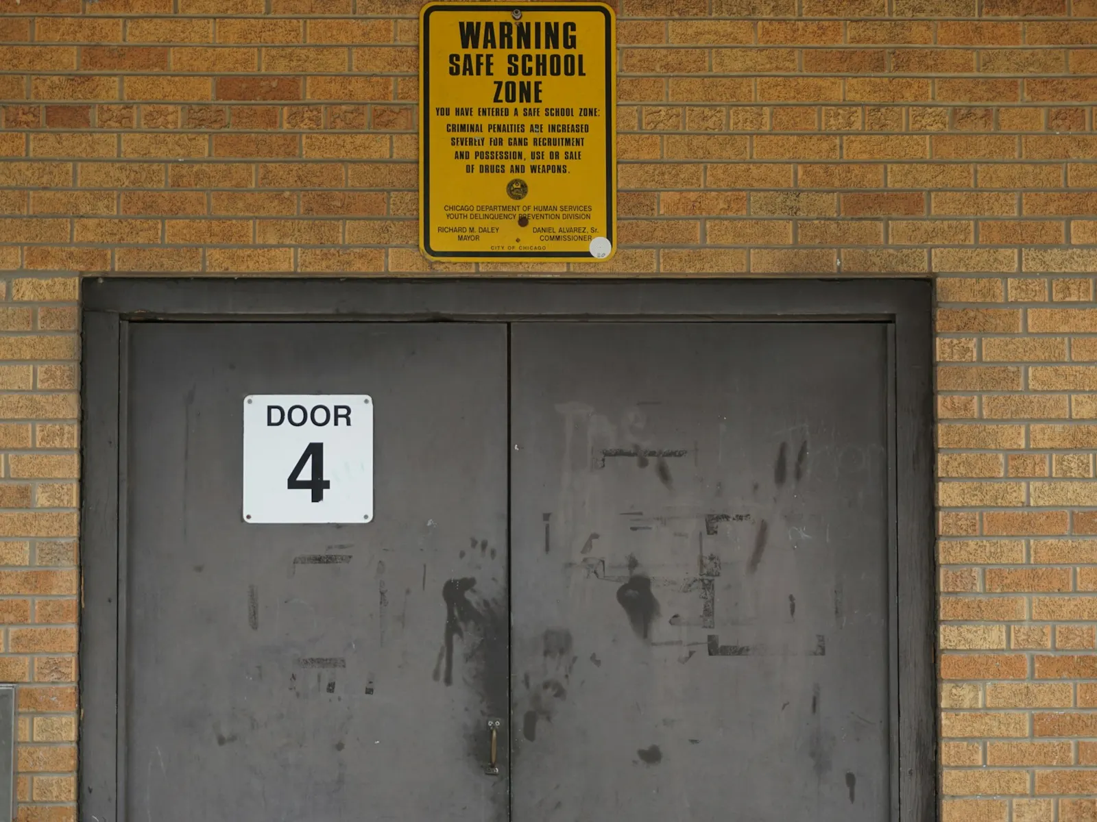 School building double doors with a door number sign and a safe school zone notice
