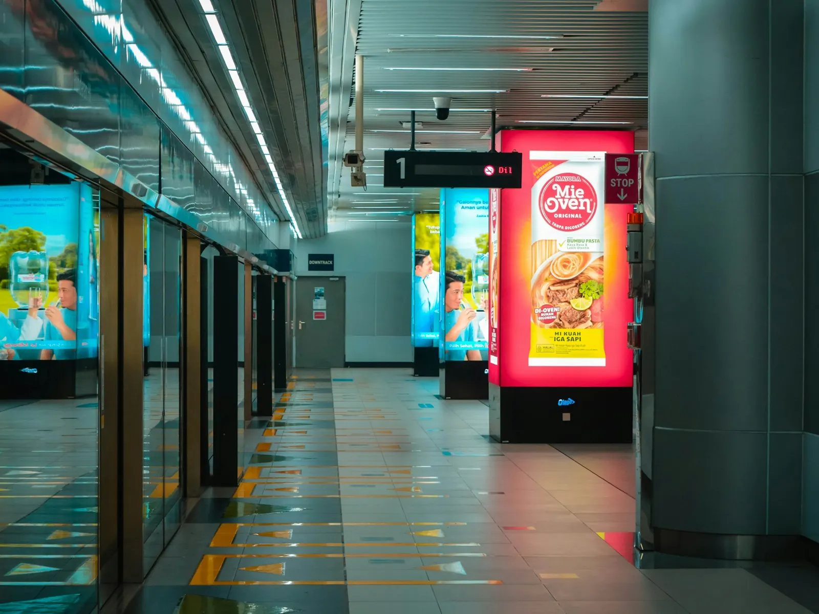 Digital signage screens showing bright advertising content along a modern metro station corridor
