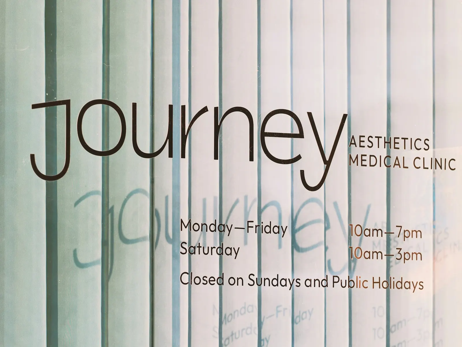 Clinic name and opening hours in elegant lettering on a frosted glass door at a medical clinic