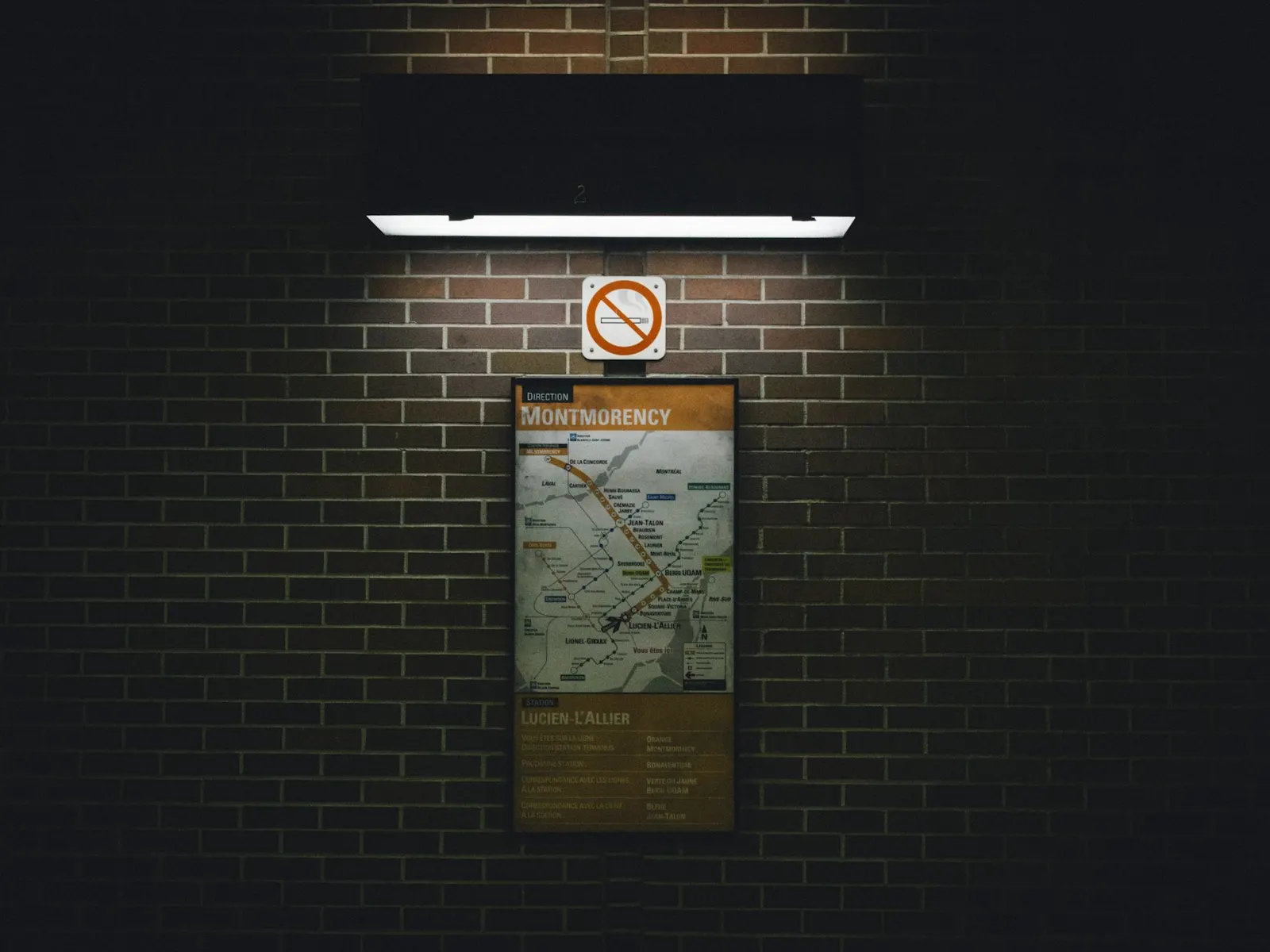 Framed plan board mounted on a dark brick wall under a lamp