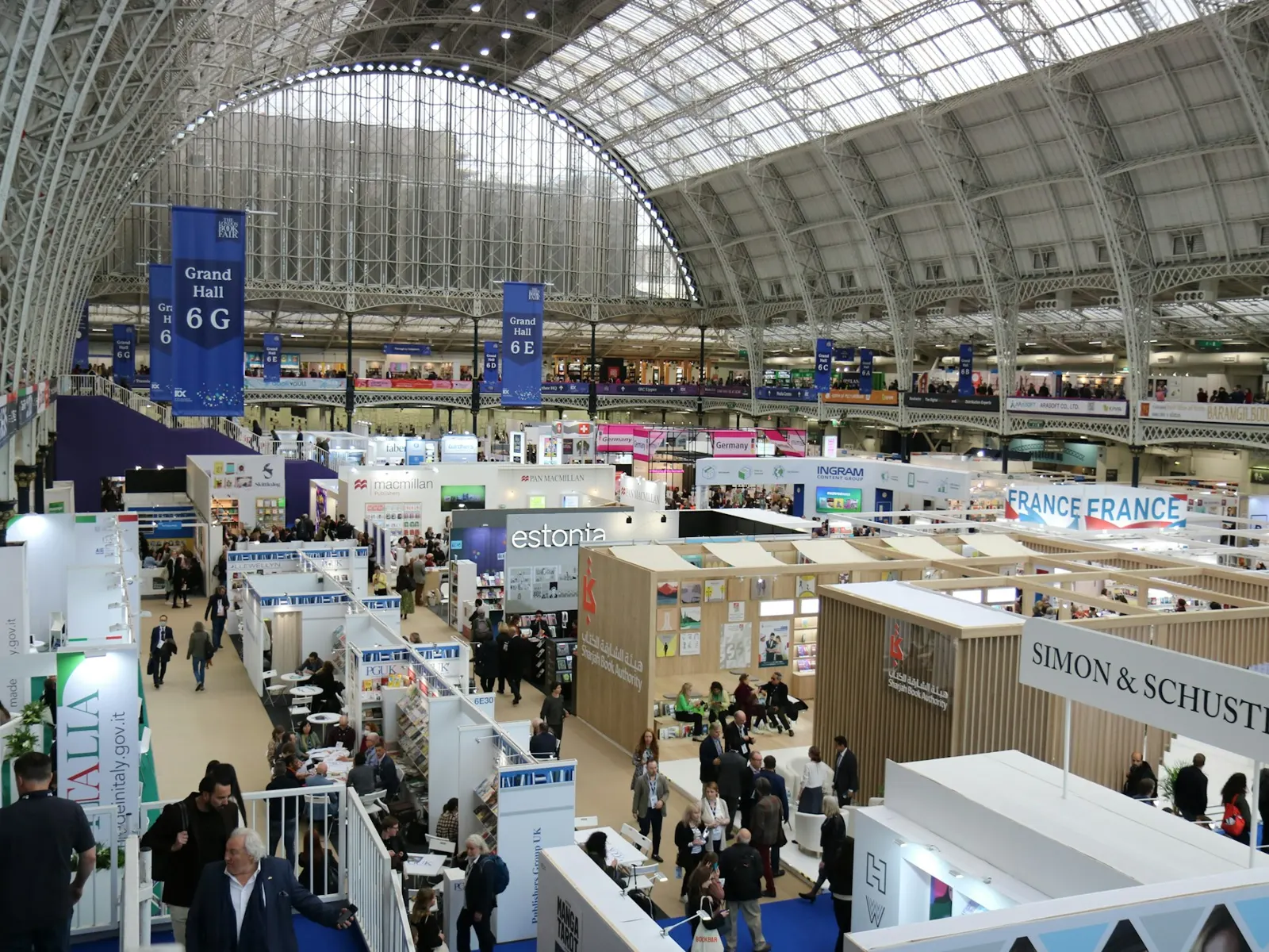 Large exhibition hall with suspended hanging banners above rows of trade show booths