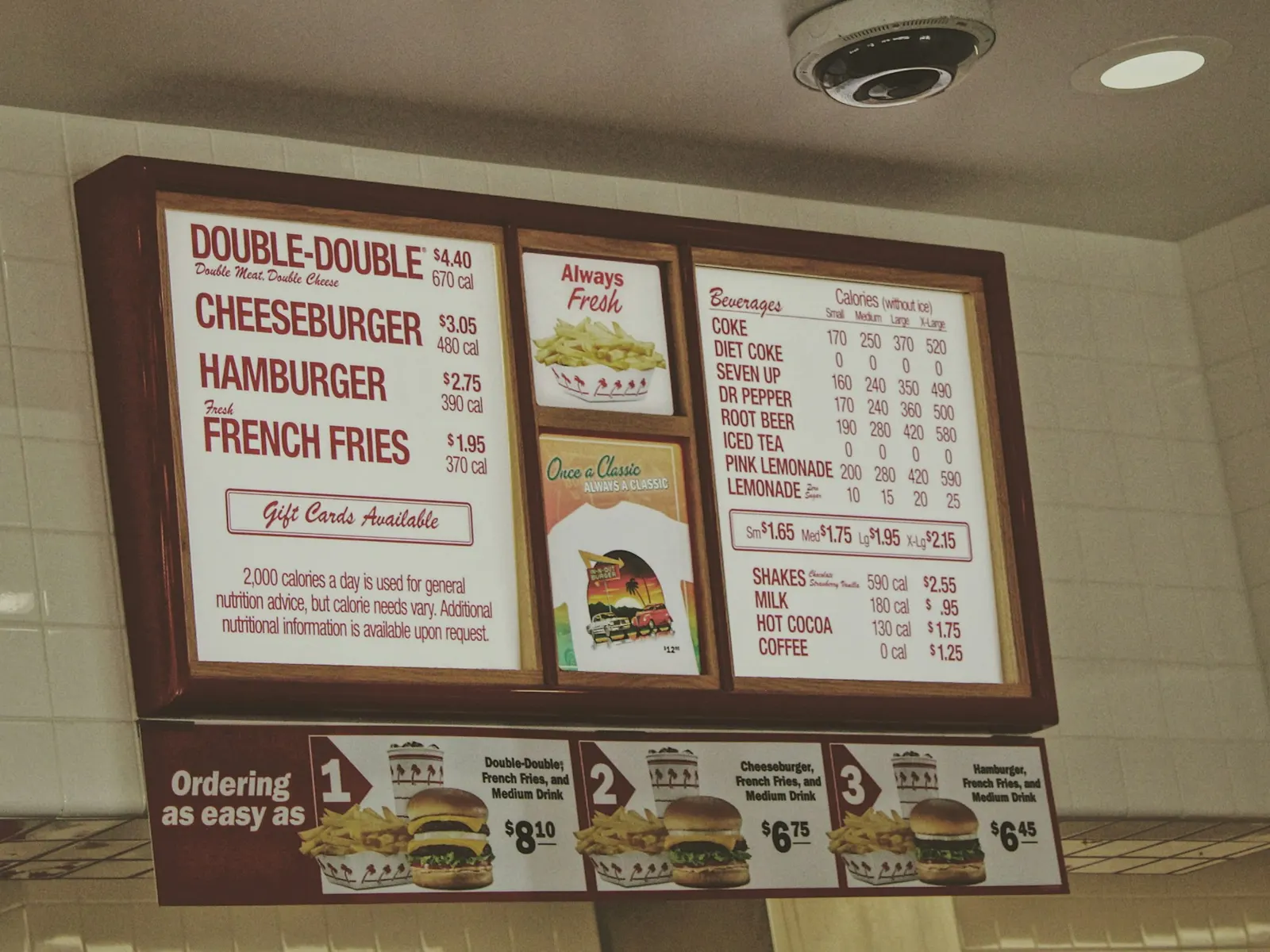 Backlit illuminated menu board panels with burger photos and prices above a restaurant counter