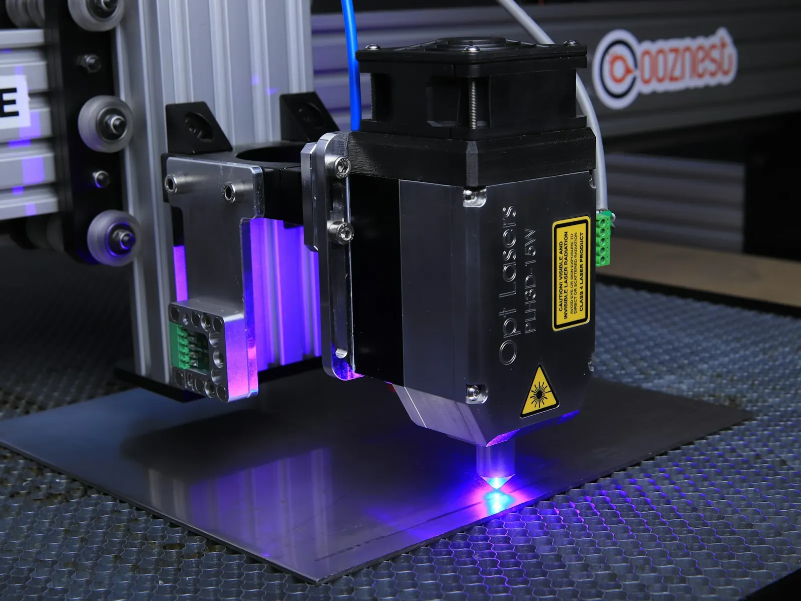 Laser engraving machine marking a metal plate with a blue beam in a workshop