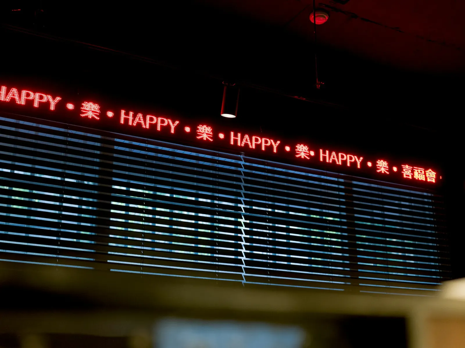 Red LED ticker sign scrolling a repeated message above a dark shop window