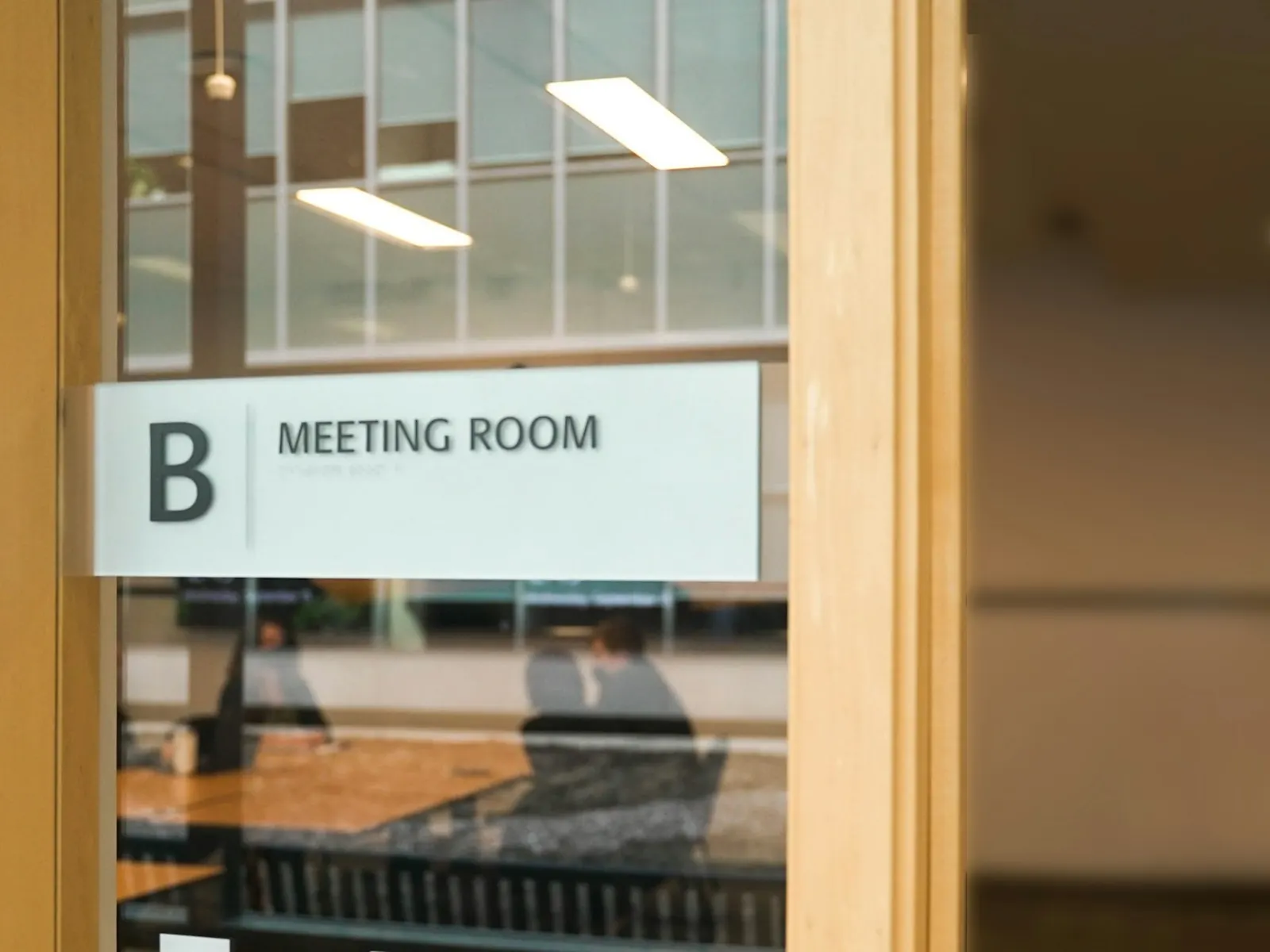 Meeting room sign with letter B on a glass door in a modern office