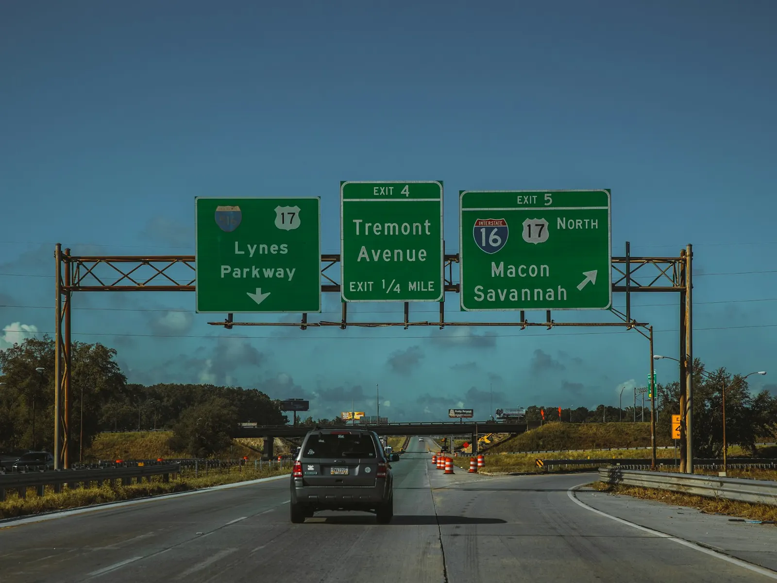 Overhead gantry signs with green highway direction panels spanning a multi-lane motorway