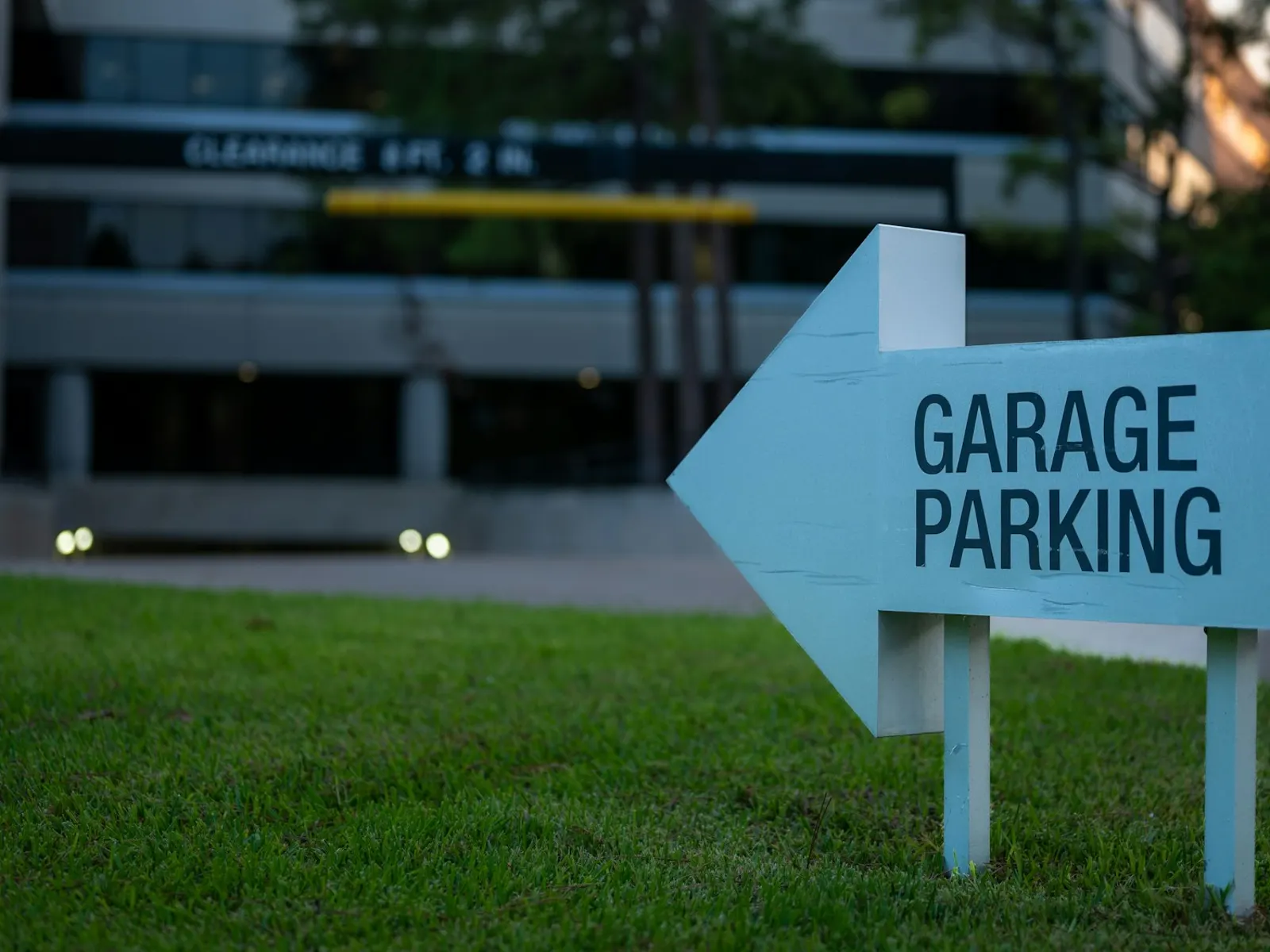 Garage parking entrance sign shaped as an arrow on a lawn beside an office building