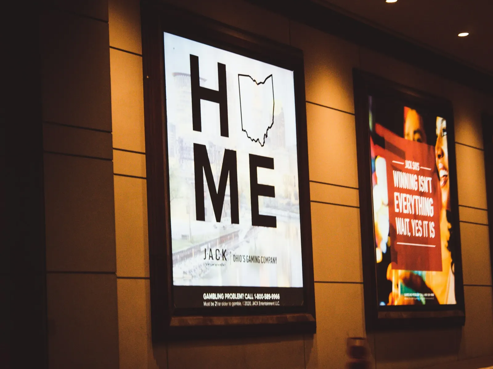 Backlit poster lightboxes glowing along a warm-toned wall in a dim corridor