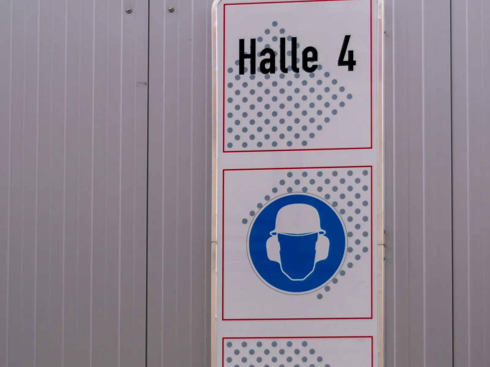 PPE requirement sign panel with hard hat mandatory symbol fixed to an industrial wall