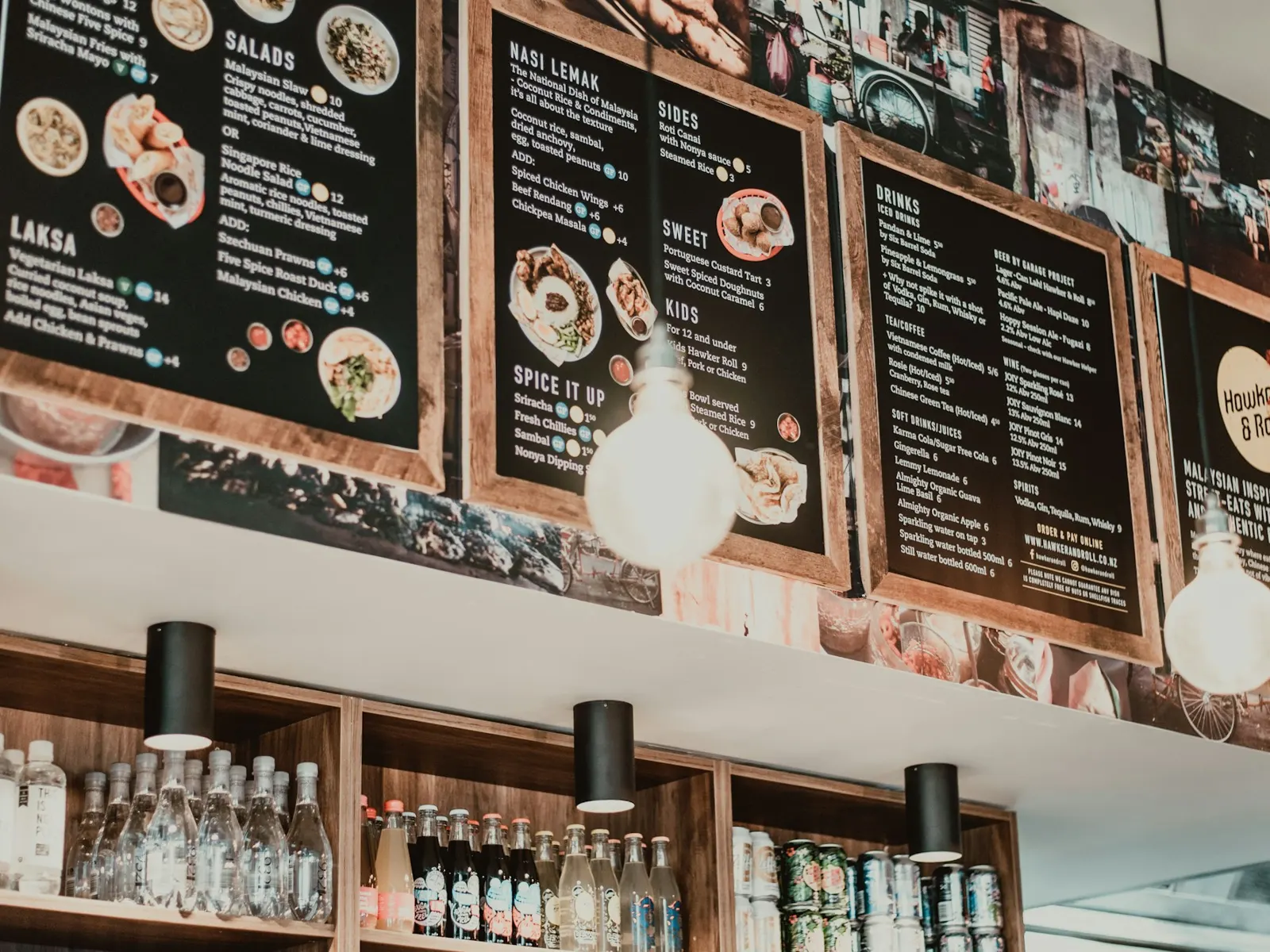 Row of printed menu boards with food photos mounted above a cafe bar