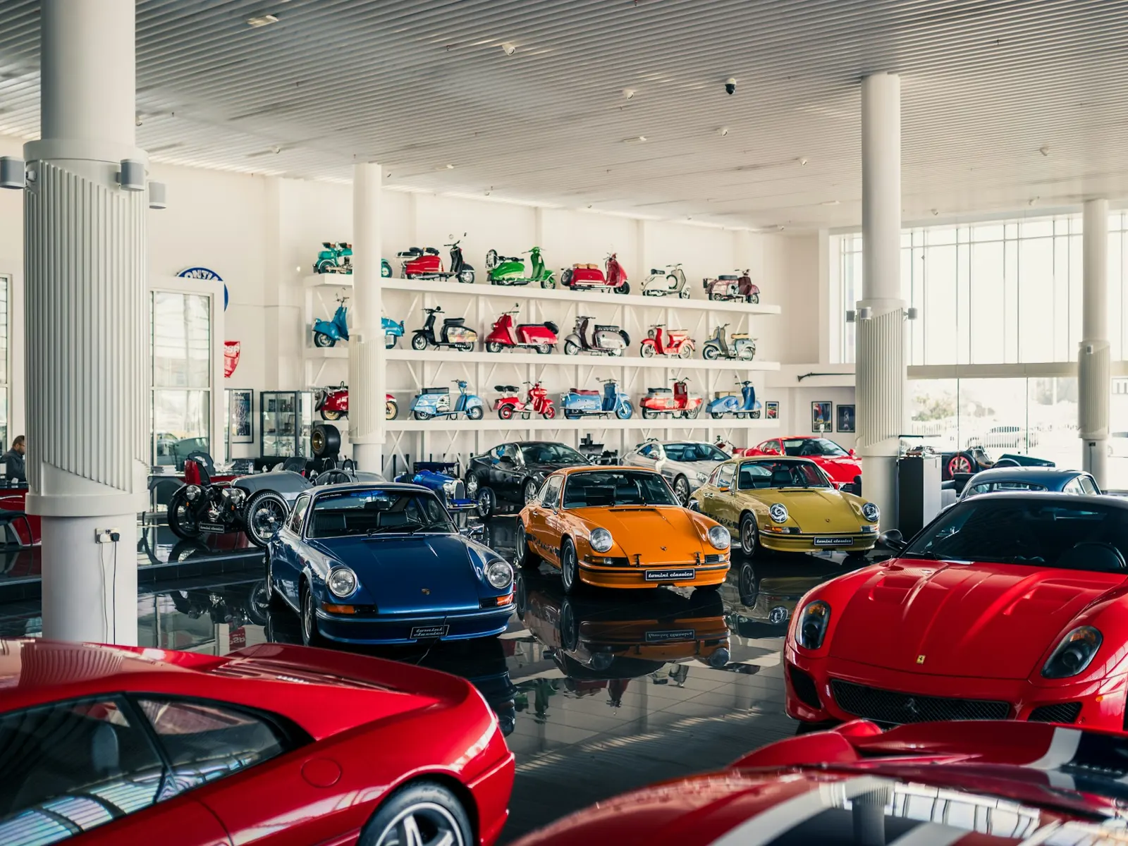 Bright modern car showroom interior with sports cars and display shelving under white ceilings