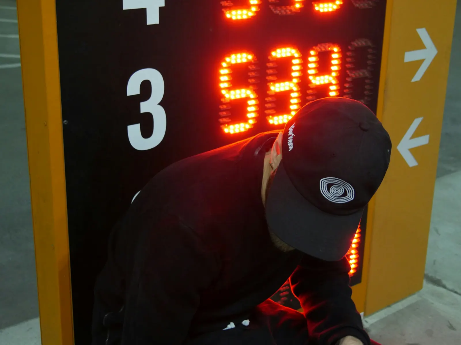 Technician servicing an illuminated LED price sign during routine signage maintenance work