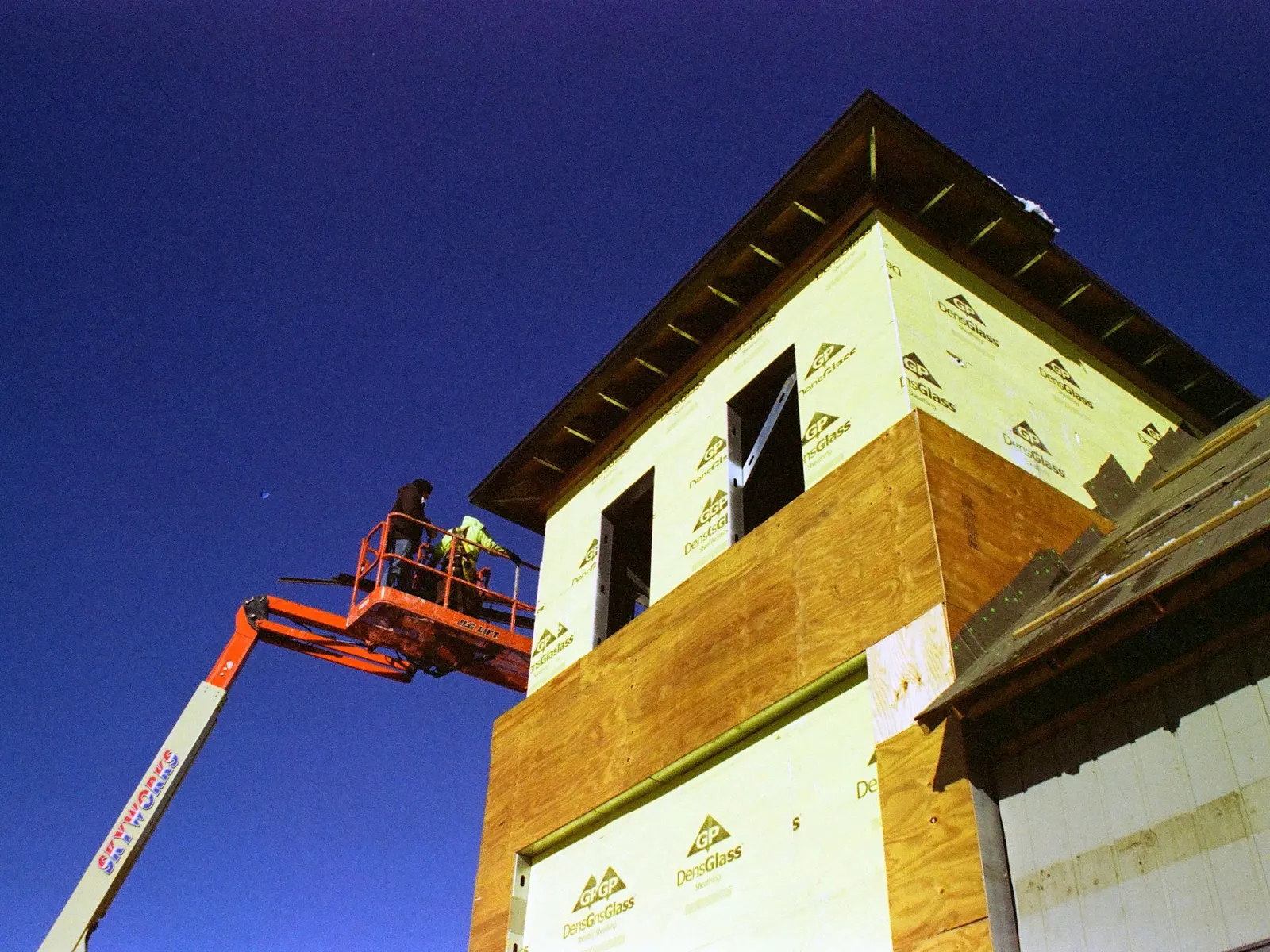 Boom lift raising a worker to a building facade for high-level installation work