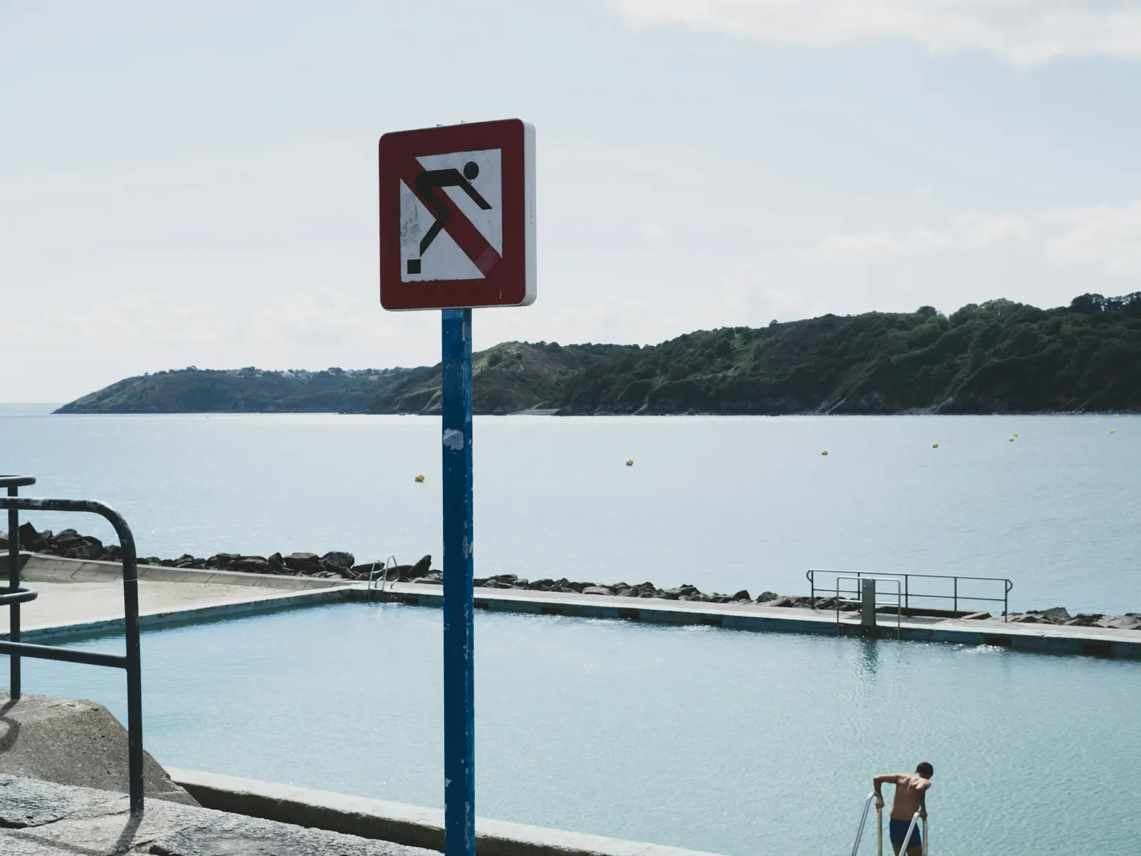 No diving swimming pool safety sign on a pole beside an outdoor pool