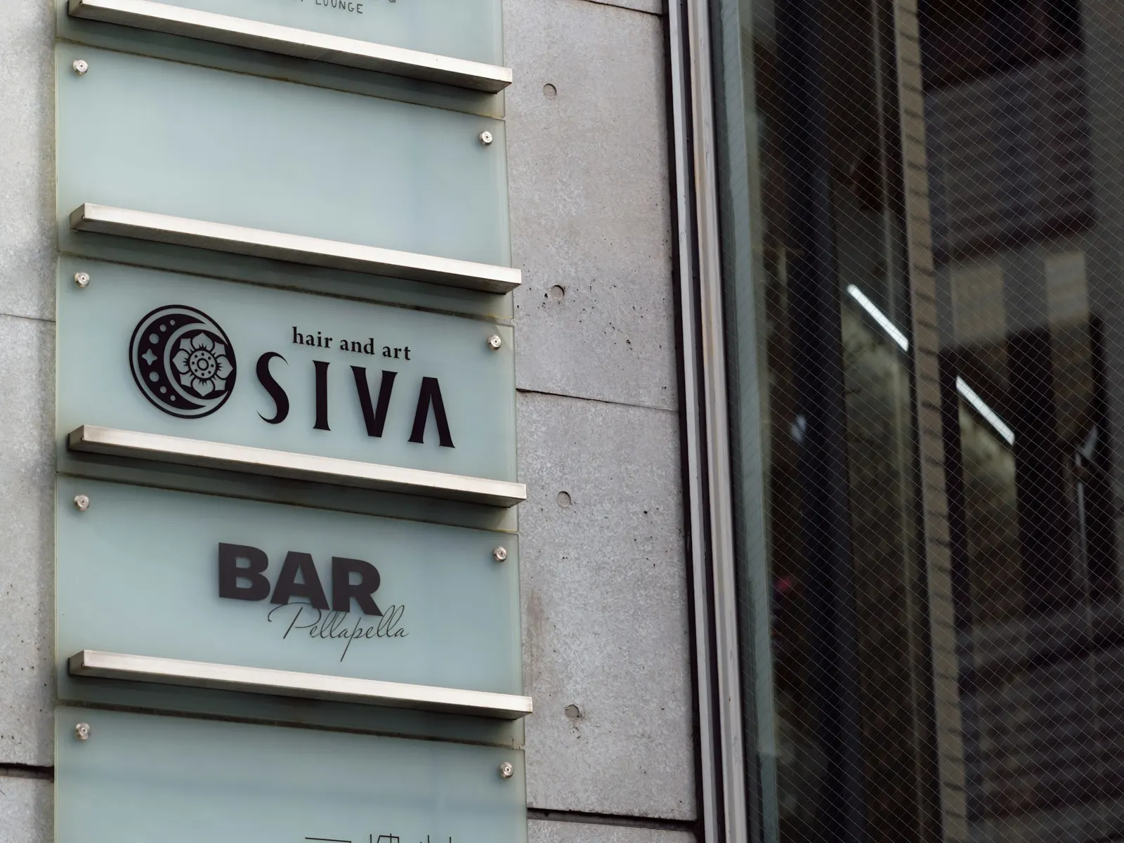 Stacked tenant name plates fixed to a stone wall beside a building entrance