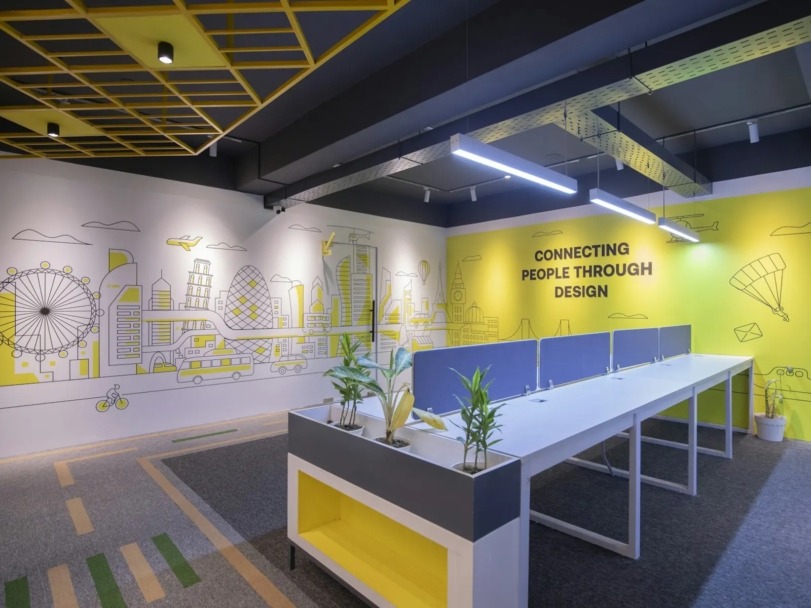 Office wall graphics with printed line art and slogan above a row of desks