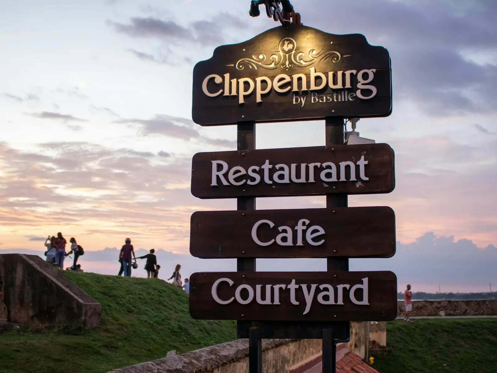Dark wooden signboards with light lettering for a restaurant, cafe and courtyard at dusk
