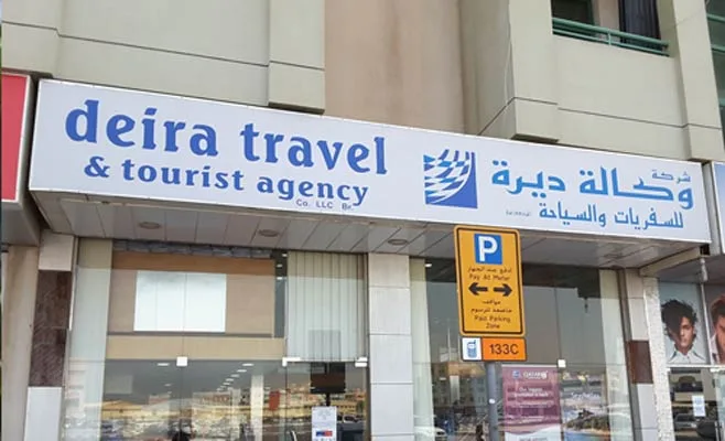 Bilingual outdoor light box fascia sign above a travel agency shopfront